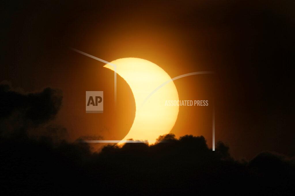 Seth Wenig A partially eclipsed sun peaks out from behind a cloud as it rises over lower Manhattan in New York, Thursday, June 10, 2021. (AP Photo/Seth Wenig)