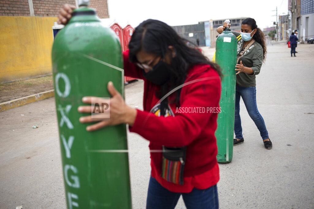 Rodrigo Abd Marlene and Rosalyn Del Aguila roll tanks filled with oxygen to a waiting car, to deliver to their mother who has tested positive for COVID-19, in the Villa El Salvador neighborhood of Lima, Peru, Wednesday, April 7, 2021, amid the new coronavirus pandemic. (AP Photo/Rodrigo Abd)