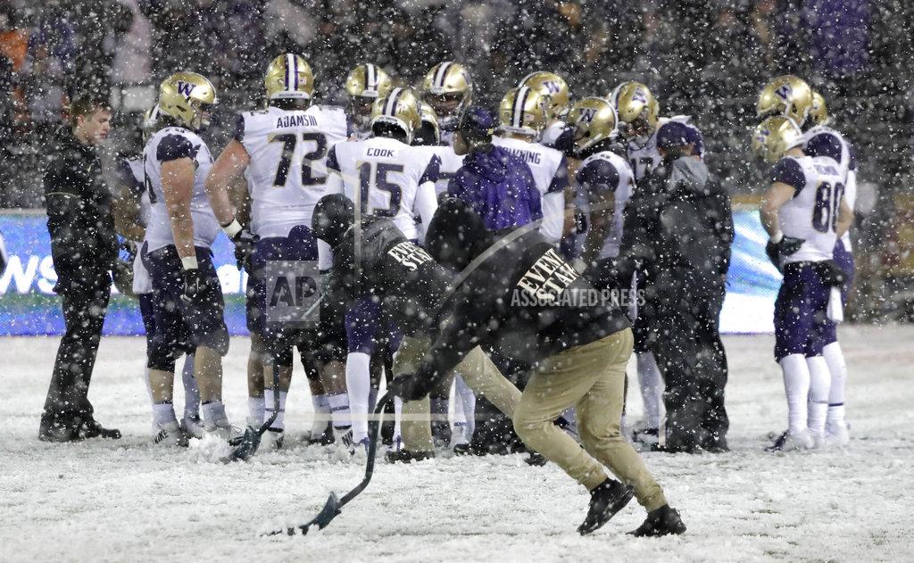 Ted S. Warren Stadium workers shovel off yard lines as Washington players huddle during the second half of an NCAA college football game against against Washington State, Friday, Nov. 23, 2018, in Pullman, Wash. (AP Photo/Ted S. Warren)