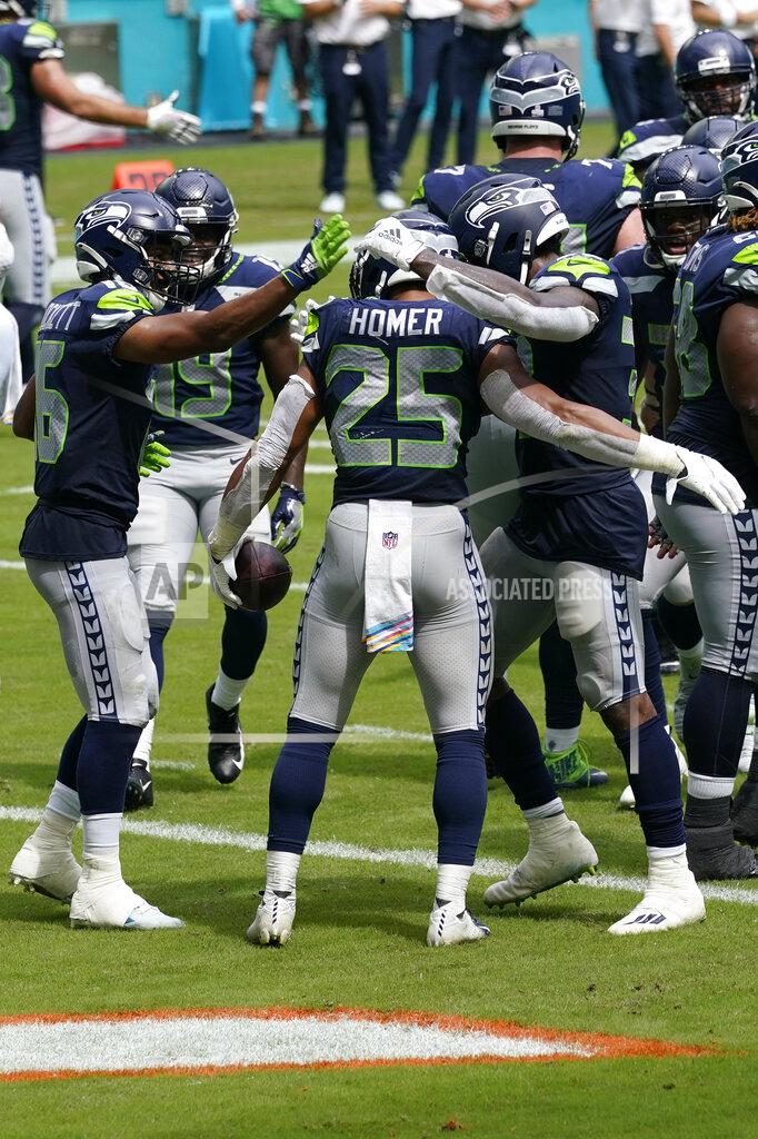 Lynne Sladky Teammates congratulate Seattle Seahawks running back Travis Homer (25) after Homer scored a touchdown during the first half of an NFL football game against the Miami Dolphins, Sunday, Oct. 4, 2020, in Miami Gardens, Fla. (AP Photo/Lynne Sladky)