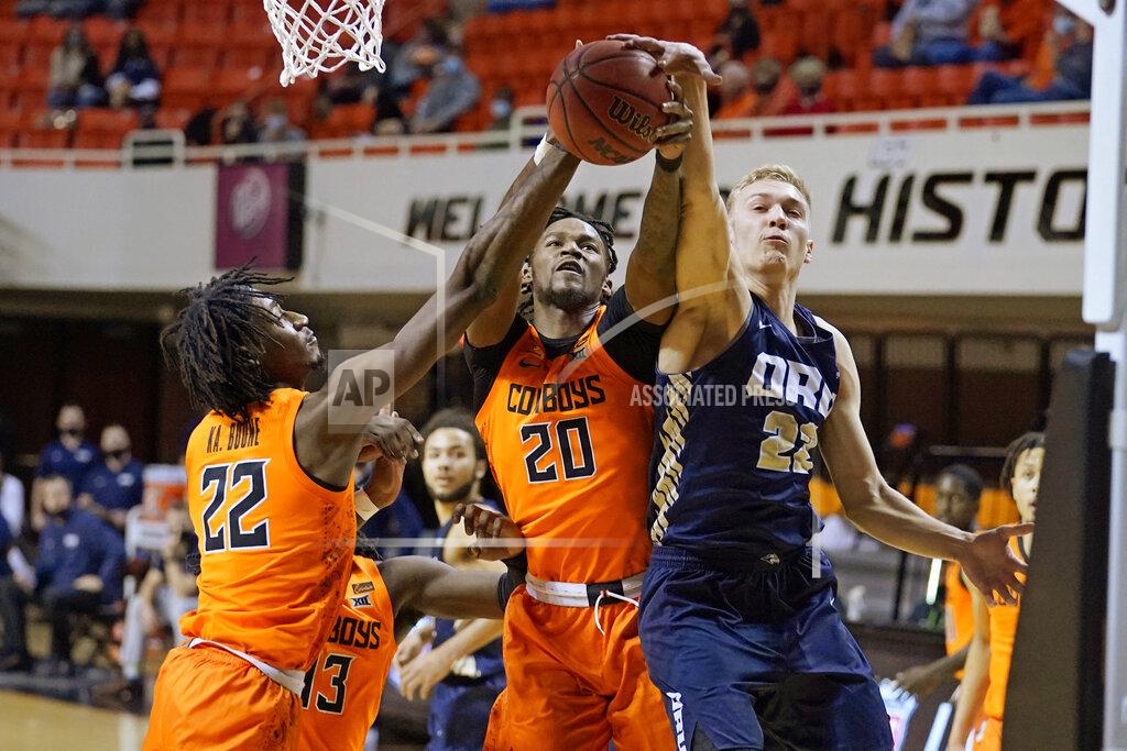 Sue Ogrocki Oklahoma State forward Kalib Boone, left, and guard Keylan Boone (20) and Oral Roberts forward Francis Lacis, right, reach for a rebound during the first half of an NCAA college basketball game Tuesday, Dec. 8, 2020, in Stillwater, Okla. (AP Photo/Sue Ogrocki)