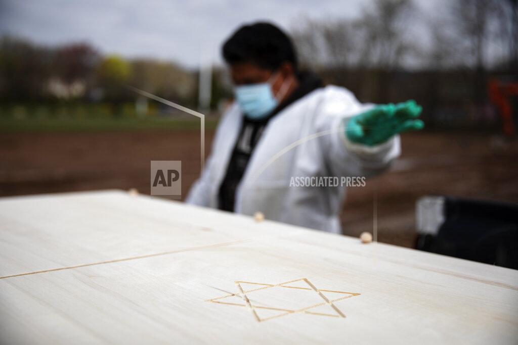 David Goldman Gravedigger Thomas Cortez directs his coworker where to stop the pickup truck carrying a casket as it's brought to a plot for burial at Hebrew Free Burial Association's Mount Richmond Cemetery in the Staten Island borough of New York, Wednesday April 8, 2020. Two of Cortez' friends have fallen ill and he and his colleagues worry they will too. It is sad work, he admits, but it must continue. Another funeral is about to begin. (AP Photo/David Goldman)