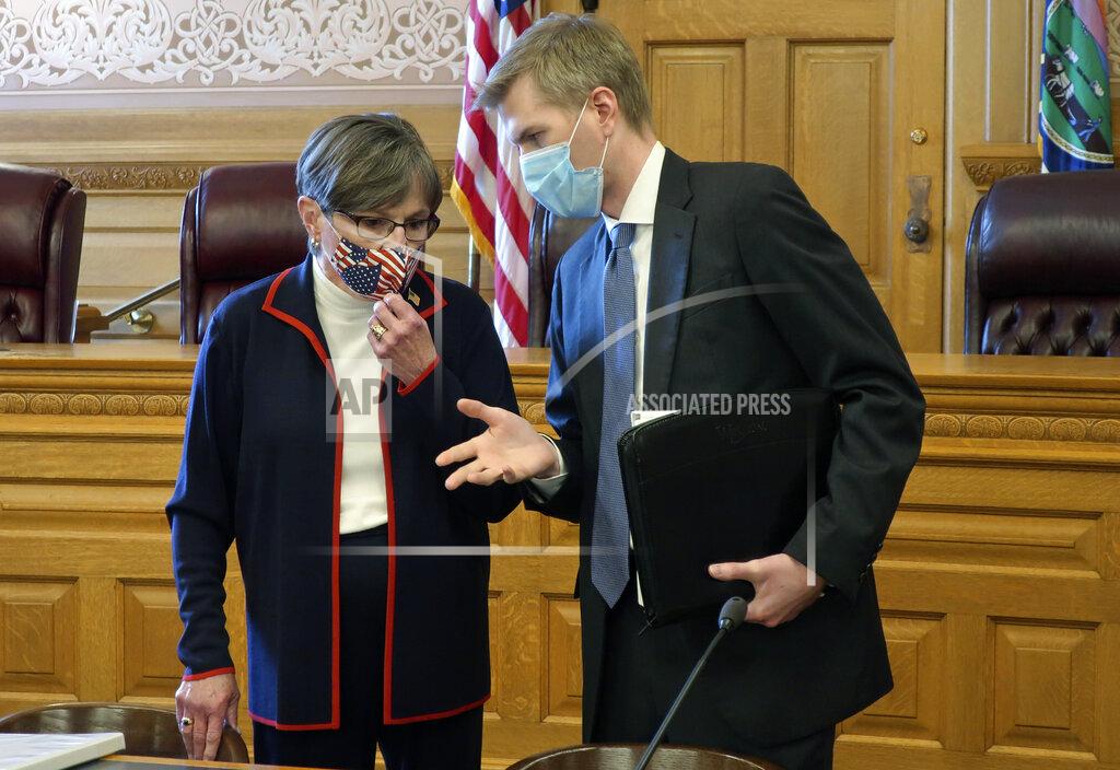 Kansas Gov. Laura Kelly, left, confers with Clay Britton, her chief attorney, before a meeting with legislative leaders about an executive order she issued to require people to wear masks in public, Thursday, July 2, 2020, at the Statehouse in Topeka, Kan. Kelly says she's worried that if the state doesn't reverse a recent surge in reported coronavirus cases, the state won't be able to reopen K-12 schools in August. (AP Photo/John Hanna)