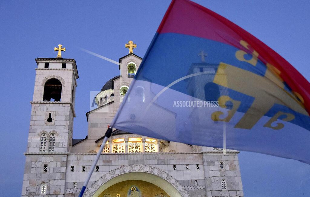 Risto Bozovic An opposition supporter waves an old Serbian flag during church-led protest in front of the Serbian Orthodox Church of Christ's Resurrection in Podgorica, Montenegro, Thursday, Aug. 27, 2020. Montenegro is holding a parliamentary election this weekend with the pro-Western government facing pressure over the new coronavirus outbreak and ongoing tensions in relations with Serbia and the Serbian Orthodox Church because of a religious property law. (AP Photo/Risto Bozovic)