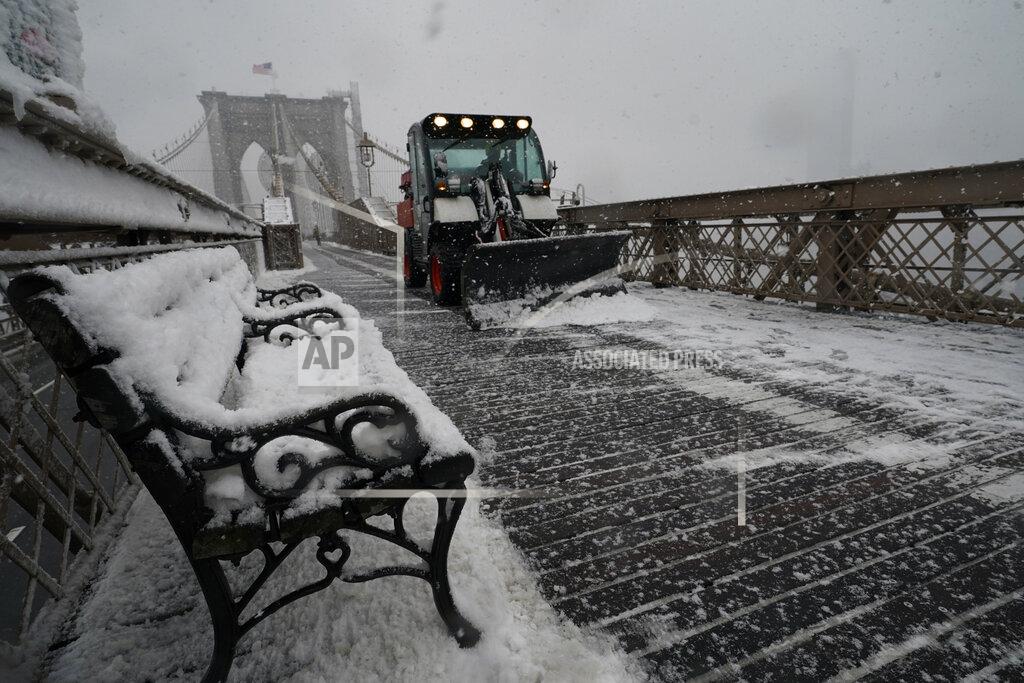 Kathy Willens A snowplow makes it's way across the pedestrian walkway of the Brooklyn Bridge during a snowstorm, Sunday, Feb. 7, 2021, in New York. It was the second major snowstorm in less than week to hit the area. (AP Photo/Kathy Willens)
