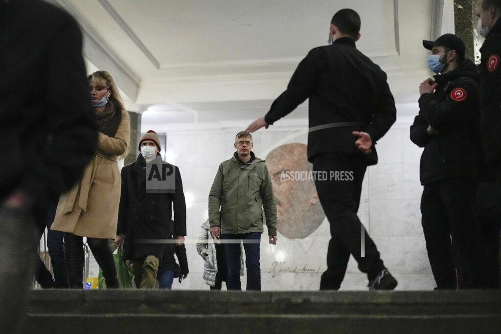Pavel Golovkin Moscow's metro security personnel, right, stops a passenger without a protective mask, with a portrait of Soviet founder Vladimir Lenin in the background, in Moscow, Russia, Monday, Oct. 25, 2021. Russia reported another daily record of confirmed coronavirus cases Monday as a surge in infections has prompted the Kremlin to tell most people to stay away from work starting later this week. (AP Photo/Pavel Golovkin)