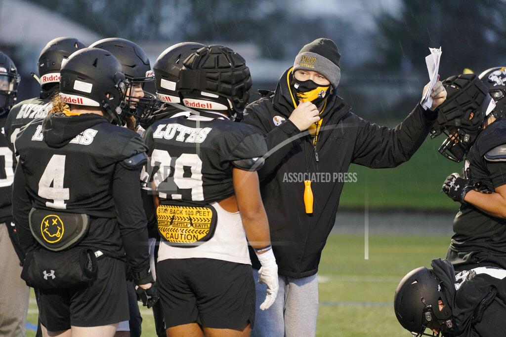 Ted S. Warren Brant McAdams, center, football coach at Pacific Lutheran, wears a mask as he talks to players during practice Tuesday, Feb. 2, 2021, in Tacoma, Wash. For all the attention heaped on the FBS level of college football last fall as it tried to play, it will not be the only college football during the 2020-21 sports calendar as a handful of NCAA Division III and NAIA programs begin some form of a winter/spring season Saturday, Feb. 6. (AP Photo/Ted S. Warren)