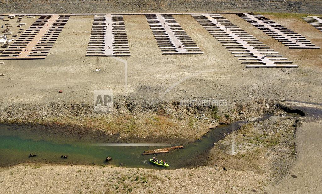 Josh Edelson FILE - Kayakers navigate a narrow section of water near boat docks sitting on dry land at the Browns Ravine Cove area of drought-stricken Folsom Lake, in Folsom, Calif., Saturday, May 22, 2021. California Gov. Gavin Newsom threatened Monday, May 23, 2022, to impose mandatory, statewide restrictions on water use if people don't start using less on their own as the drought drags on and the hotter summer months approach. (AP Photo/Josh Edelson,File)