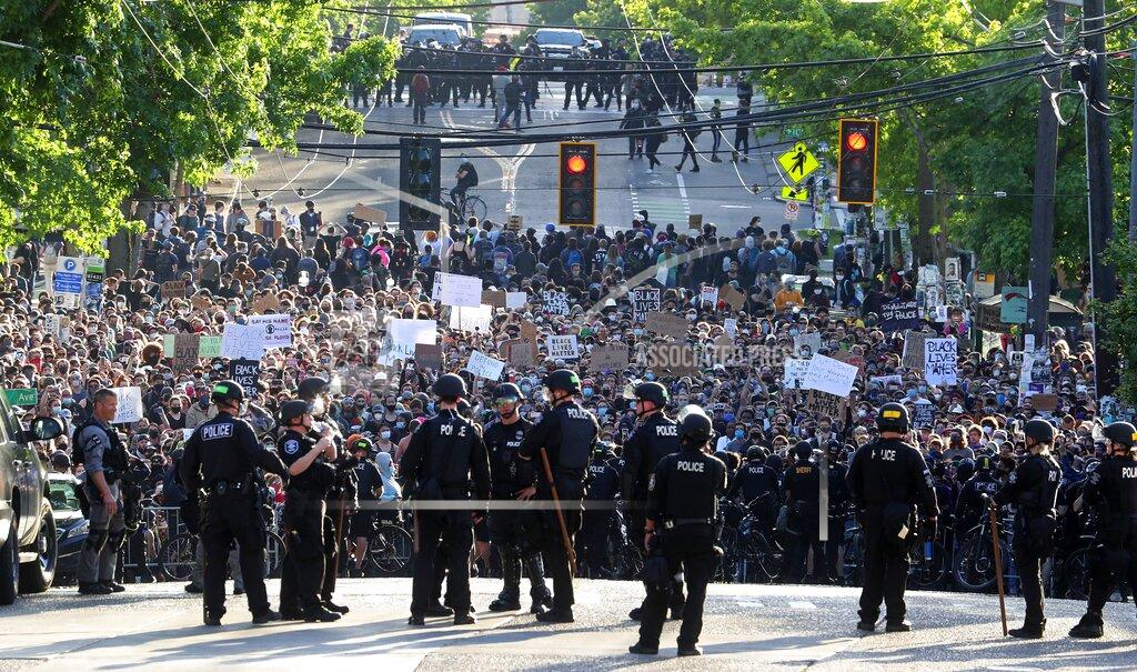 File - In this June 1, 2020 file photo a sea of peaceful protesters are kept back from the Seattle Police Department's East Precinct on Capitol Hill, by a two-block buffer of officers and gates, seen in the foreground in Seattle, as demonstrations continue, sparked by the death of George Floyd in Minneapolis. (Ken Lambert/The Seattle Times via AP,File)