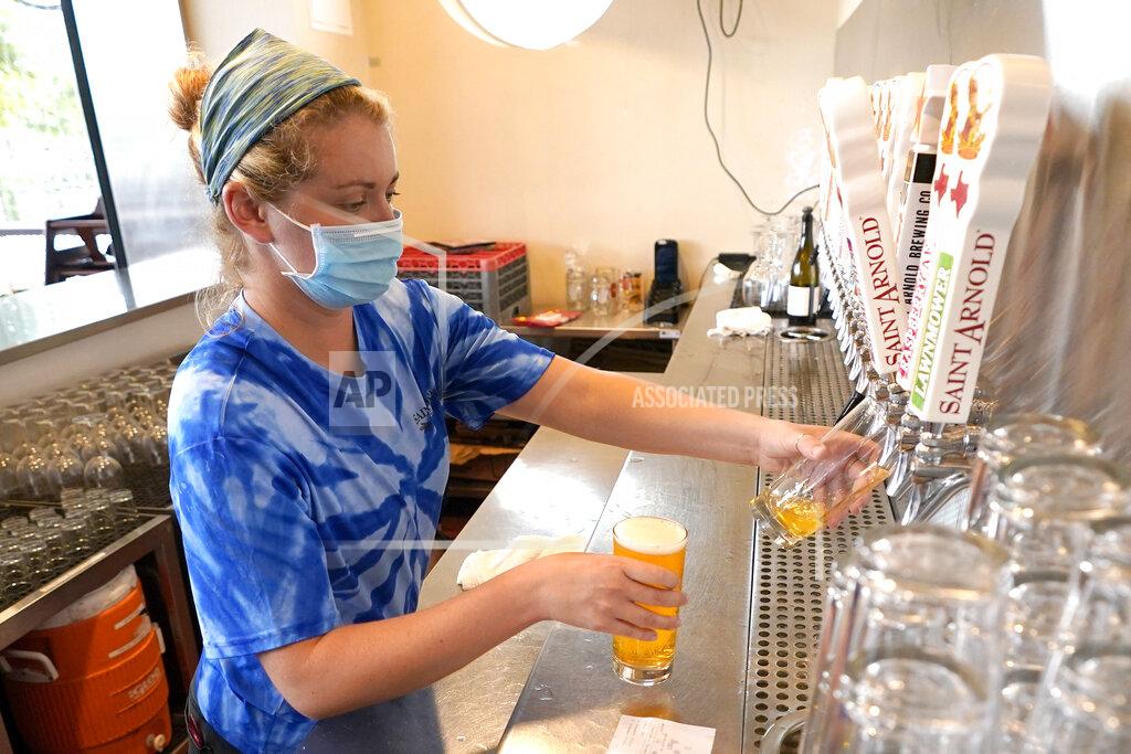 David J. Phillip Bartender Katie McGranahan pours a beer at the Saint Arnold Brewing Company Friday, June 26, 2020, in Houston. Texas Gov. Greg Abbott announced Friday that he is shutting bars back down and scaling back restaurant capacity to 50%, in response to the increasing number of COVID-19 cases in Texas.(AP Photo/David J. Phillip)