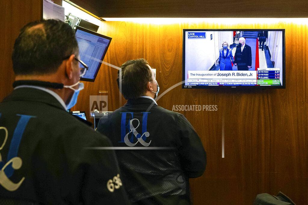 Colin Ziemer In this photo provided by the New York Stock Exchange, traders watch as the presidential inaugural plays on a screen, in a booth on the trading floor, Wednesday, Jan. 20, 2021. U.S. stocks are rallying to records Wednesday on encouraging earnings reports and continued optimism that new leadership in Washington will mean more support for the struggling economy. (Colin Ziemer/New York Stock Exchange via AP)