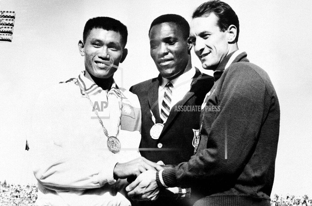 Uncredited FILE - In this Sept. 7, 1960, file photo, Rafer Johnson of Kingsburg, Calif., is flanked by runners-up, Chuan-Kwang Yang, left, of Taiwan, and Vasily Kuznetsov of Russia, as they join in three-way handshake after receiving medals for the decathlon event of the Olympics in Rome, Italy. Rafer Johnson, who won the decathlon at the 1960 Rome Olympics and helped subdue Robert F. Kennedy's assassin in 1968, died Wednesday, Dec. 2, 2020. He was 86. He died at his home in the Sherman Oaks section of Los Angeles, according to family friend Michael Roth. (AP Photo)