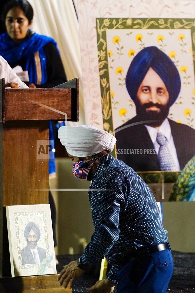 Ross D. Franklin Rana Singh Sodhi, brother of Balbir Singh Sodhi, moves a portrait of his brother at a memorial service on the 20th anniversary of the murder of Balbir Singh Sodhi Wednesday, Sept. 15, 2021, in Mesa, Ariz. Sikh businessman Balbir Singh Sodhi was helping plant a flower bed at his Arizona gas station when he was shot dead by a man seeking to avenge 9/11. Mistaken for an Arab Muslim because of his turban and beard, Sodhi was the first person to die in a wave of bias crimes unleashed by the attacks. (AP Photo/Ross D. Franklin)