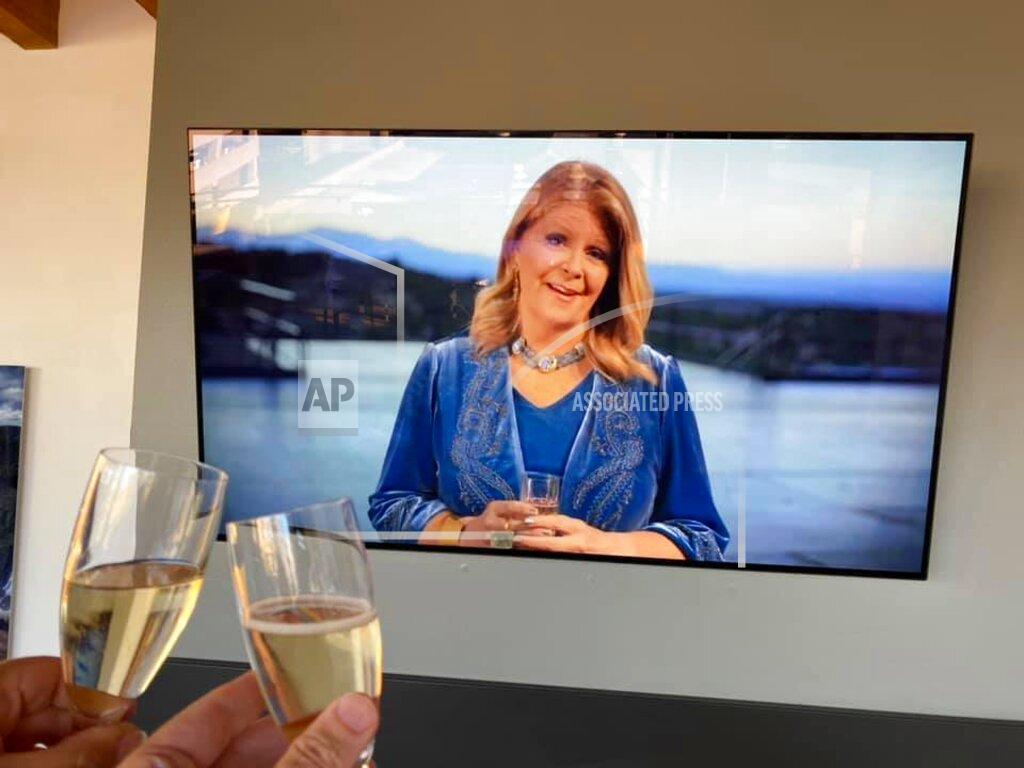 Peter Batty This July 3, 2020 image provided by Peter Batty shows him and his wife toasting as they celebrate their anniversary and watch mezzo-soprano Susan Graham host opening night of the Santa Fe Opera on their television in Denver, Colorado. The famed opera is offering a series of virtual performances after being forced to cancel the 2020 season due to the coronavirus pandemic. The Saturday night events are meant to celebrate the five originally-scheduled operas that would have been performed this summer. (Peter Batty via AP)