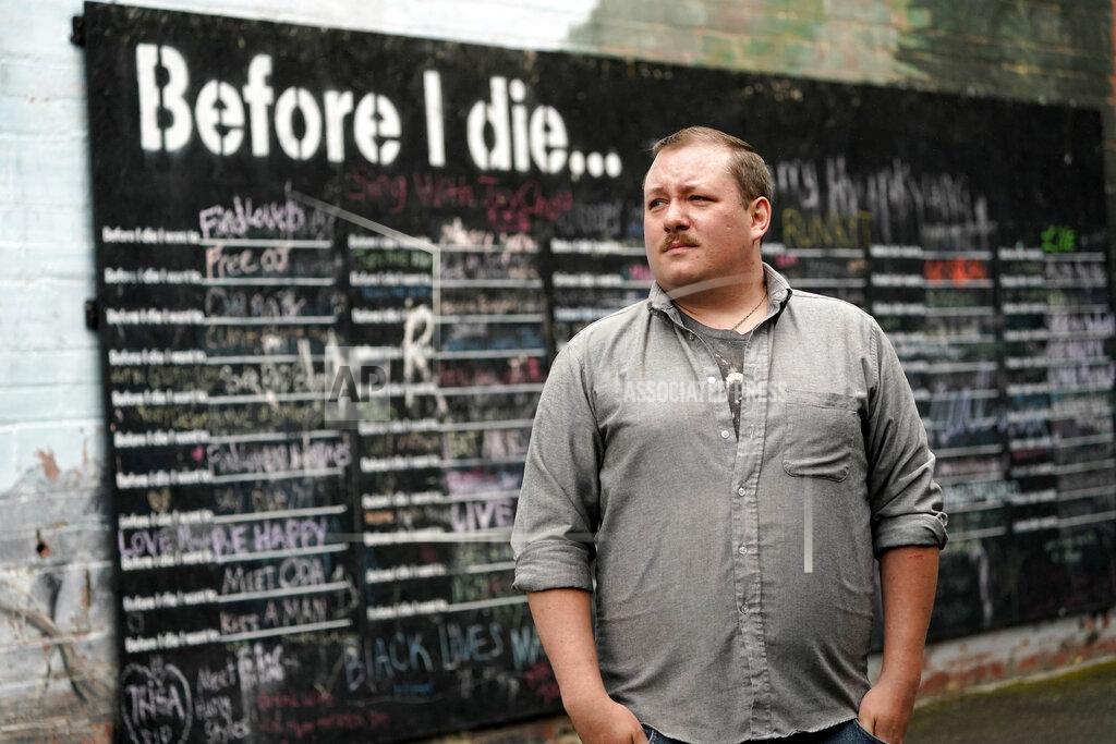 Elaine Thompson Nate Mullins, a former bartender from Oak, Harbor, Wash., who quit his job last November after clashing with managers over enforcing mask rules, poses for a photo near a street mural Monday, May 17, 2021, in Mount Vernon, Wash. There's a wild card in the push to return to post-pandemic life: many workers don't want to return to the jobs they once had. Mullins' unemployment checks don't match what he was making at the bar, but they're enough to get by while he looks for jobs that would provide health care and retirement benefits. (AP Photo/Elaine Thompson)