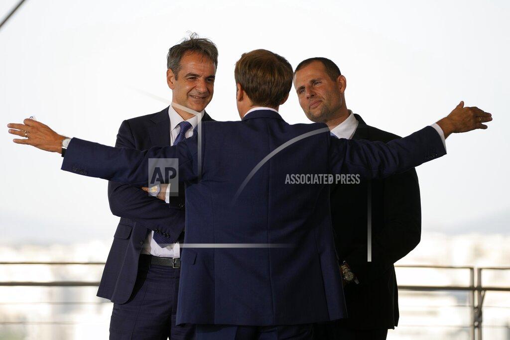 Thanassis Stavrakis Greek Prime Minister Kyriakos Mitsotakis, left, and his Maltese counterpart Robert Abela, right, listen to French President Emmanuel Macron during the EUMED 9 summit at the Stavros Niarchos Foundation Cultural Center in Athens, Friday, Sept. 17, 2021. Nine European countries on the Mediterranean are holding a summit in Athens to discuss issues ranging from climate change and the pandemic response to migration and Afghanistan. (AP Photo/Thanassis Stavrakis)