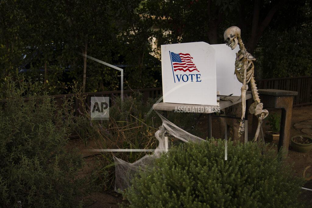 A skeleton stands next to a mock polling booth as part of Halloween decoration in Pasadena, Calif., Saturday, Oct. 31, 2020, as in-person voting started for most California counties this weekend. (AP Photo/Jae C. Hong)