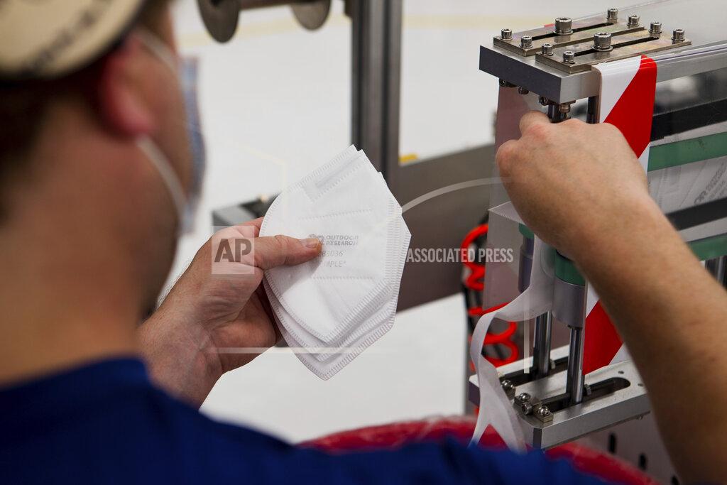 In this undated photo provided by Outdoor Research in September 2020, a worker handles filter material for face masks in Seattle. A key challenge for N95 mask manufacturers racing to meet spiking demand is scarcity of meltblown textile. (Gerardo Villalobos/Outdoor Research via AP)