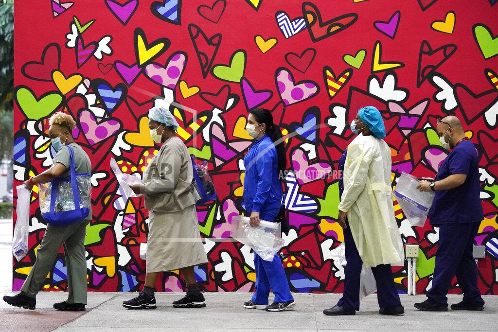 Wilfredo Lee Healthcare workers line up for free personal protective equipment in front of a mural by artist Romero Britto at Jackson Memorial Hospital, Tuesday, Sept. 22, 2020, in Miami. Hundreds of workers lined up for the PPE given out by the New York nonprofit Cut Red Tape 4 Heroes. (AP Photo/Wilfredo Lee)
