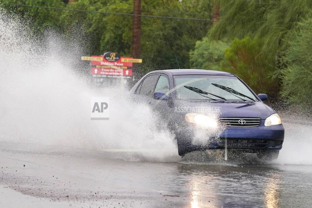 Ross D. Franklin A vehicle sprays water in the air while driving through standing water as heavy rains caused flooding, Friday, July 23, 2021, in Phoenix. (AP Photo/Ross D. Franklin)