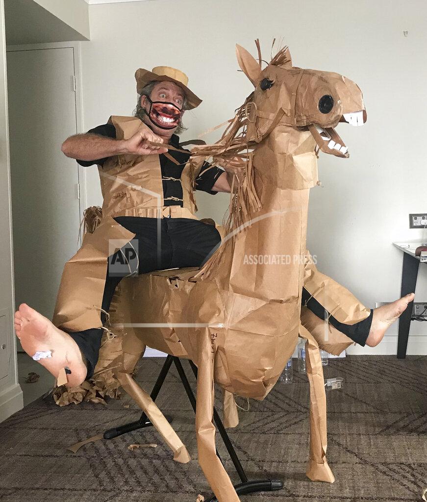 David Marriott CORRECTS NAME - David Marriott poses with his paper horse "Russel" in his hotel room in Brisbane, Australia, April 1, 2021. While in quarantine inside his Brisbane hotel room, the art director was bored and started making a cowboy outfit from the paper bags his meals were being delivered in. His project expanded to include a horse and a clingfilm villain that he has daily adventures with, in images that have gained a huge online following. (David Marriott via AP)
