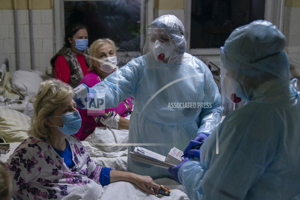 Evgeniy Maloletka A nurse checks the temperature of a patient with coronavirus in Stebnyk, western Ukraine, on Tuesday, Sept. 29, 2020. As coronavirus cases increase, every bed in the hospital in this city in western Ukraine is in use and its chief doctor is watching the surge with alarm and anguish. (AP Photo/Evgeniy Maloletka)