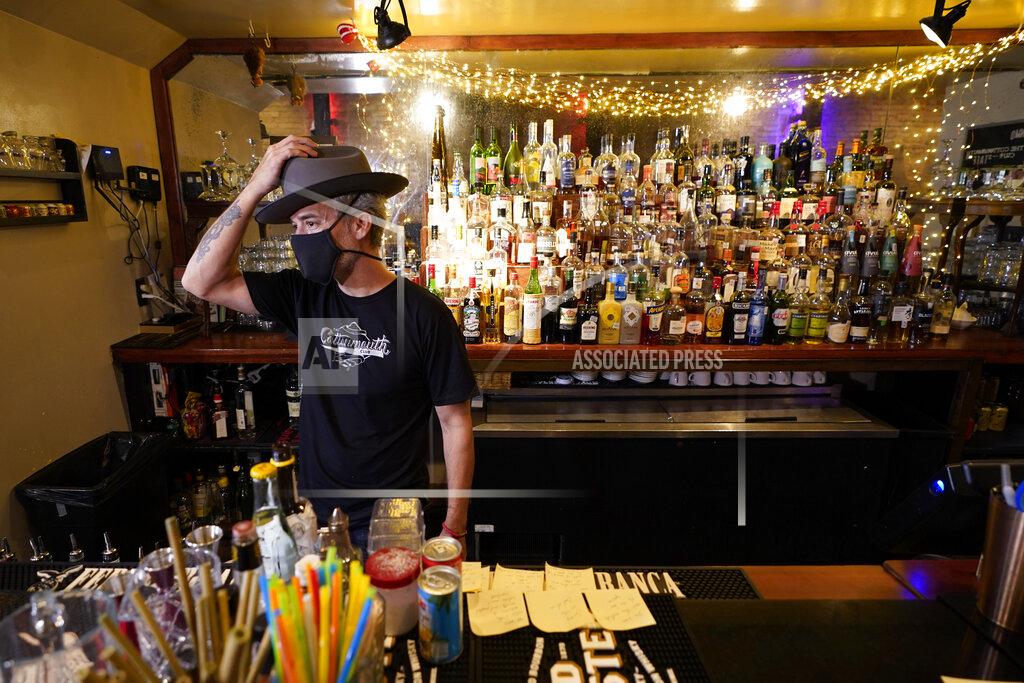 David J. Phillip Michael Neff, co-owner of the Cottonmouth Club, adjusts his hat as he stands behind the bar Tuesday, June 23, 2020, in Houston. Neff closed his downtown bar because of concerns within the industry as the number COVID-19 case continues to rise in Houston. (AP Photo/David J. Phillip)