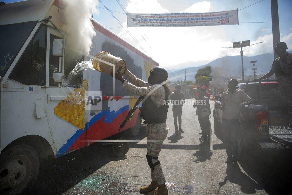 Dieu Nalio Chery A police officer attempts to extinguish a truck that was set alight by demonstrators during a protest to demand the resignation of Haiti's president Jovenel Moise in Port-au-Prince, Haiti, Wednesday, Jan. 20, 2021. Moise has one more year in power, but a growing groundswell of opposition is organizing protests and demanding he resign next month amid spiraling crime, a crumbling economy and approval of what critics say are illegal presidential decrees and unconstitutional moves, worrying many that Moise is amassing too much power as he enters his second year of rule by decree. ( AP Photo/ Dieu Nalio Chery)