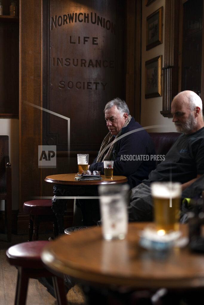 Jon Super Men drink at the Dispensary pub in Liverpool, England, Monday Oct 12, 2020. As the first area in England slapped with strict new restrictions to curb the resurgent coronavirus that have shuttered pubs and imperiled thousands of jobs, Liverpool again feels it's being punished by policies made in Britain's capital, 180 miles (290 kilometers) to the south. (AP Photo/Jon Super)