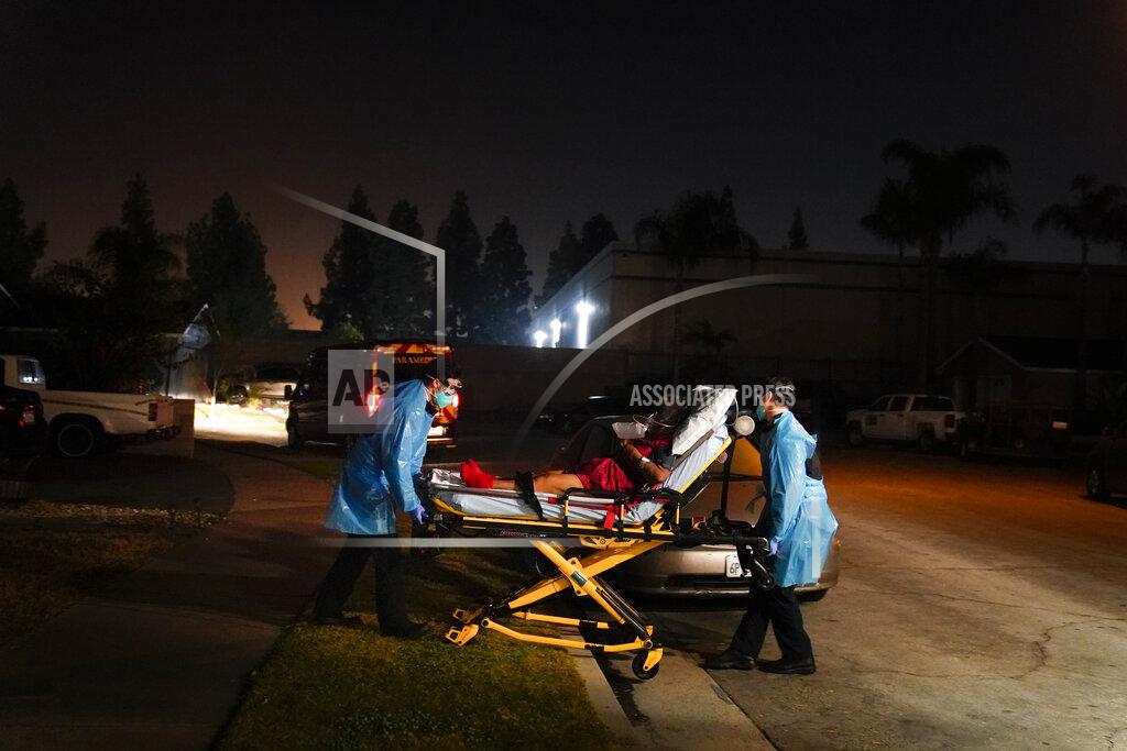 Jae C. Hong Emergency medical technicians Joshua Hammond, left, and Thomas Hoang, of Emergency Ambulance Service, transport a COVID-19 patient to an ambulance in Placentia, Calif., Friday, Jan. 8, 2021. For EMTs Thomas Hoang and Joshua Hammond, the coronavirus is constantly close. COVID-19 has become their biggest fear during 24-hour shifts in California's Orange County, riding with them from 911 call to 911 call, from patient to patient. (AP Photo/Jae C. Hong)