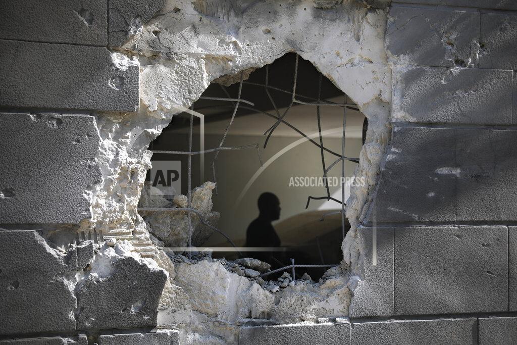 Ariel Schalit A man is seen trough a hole in a wall of a residential building after it was struck by a rocket fired from the Gaza Strip in Ashkelon, Israel, Friday, May 14, 2021. Israeli artillery pounded northern Gaza early Friday in an attempt to destroy a vast network of militant tunnels inside the territory, the military said, bringing the front lines closer to dense civilian areas and paving the way for a potential ground invasion. (AP Photo/Ariel Schalit)