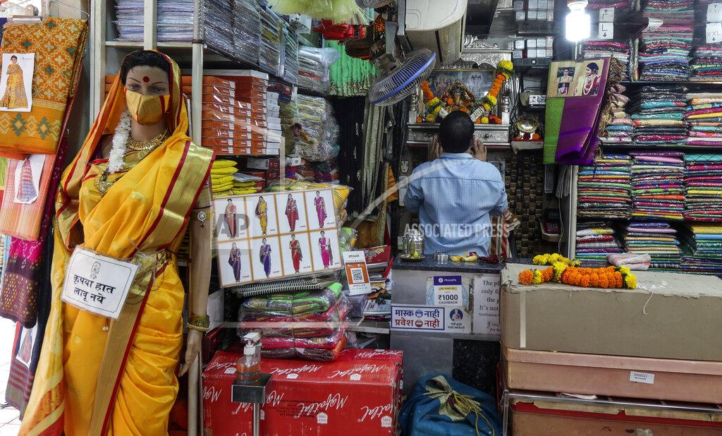 Rafiq Maqbool Signage in Marathi on a mannequin draped with a sari reads, "please don't touch" as a shopkeeper offers prayers before an image of Hindu deity Ganesh as he starts his day in Mumbai, India, Monday, June 7, 2021. . Businesses in two of India's largest cities, New Delhi and Mumbai, are reopening as part of a phased easing of lockdown measures in several states now that the number of new coronavirus infections in the country is on a steady decline. (AP Photo/ Rafiq Maqbool)