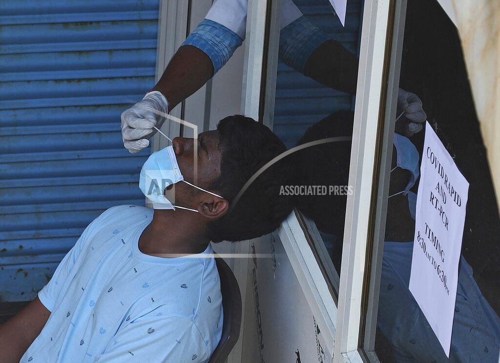 Mahesh Kumar A A health worker takes a nasal swab sample of a man to test for COVID-19 at a hospital in Hyderabad, India, Friday, April 16, 2021. India reported more than 200,000 new coronavirus cases Thursday, skyrocketing past 14 million overall as an intensifying outbreak puts a grim weight on its fragile health care system. (AP Photo/Mahesh Kumar A.)