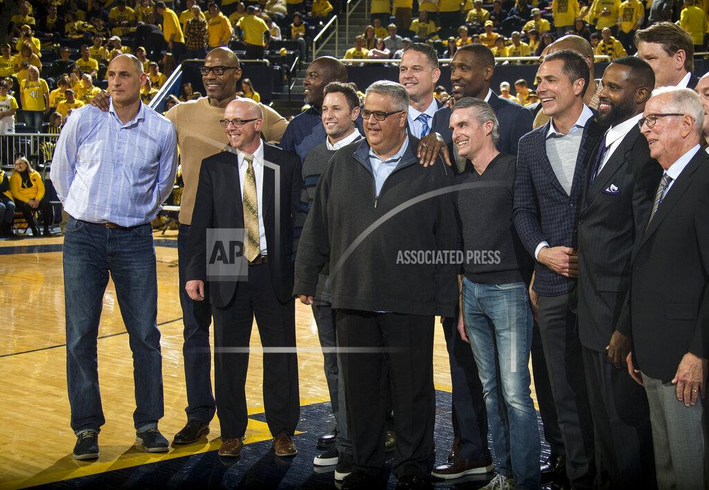 Members of the 1989 Michigan basketball team and their coach Steve Fisher, far right, pose for a photo at the half of an NCAA college basketball game between Michigan and Michigan State at Crisler Center in Ann Arbor, Mich., Sunday, Feb. 24, 2019. (AP Photo/Tony Ding)
