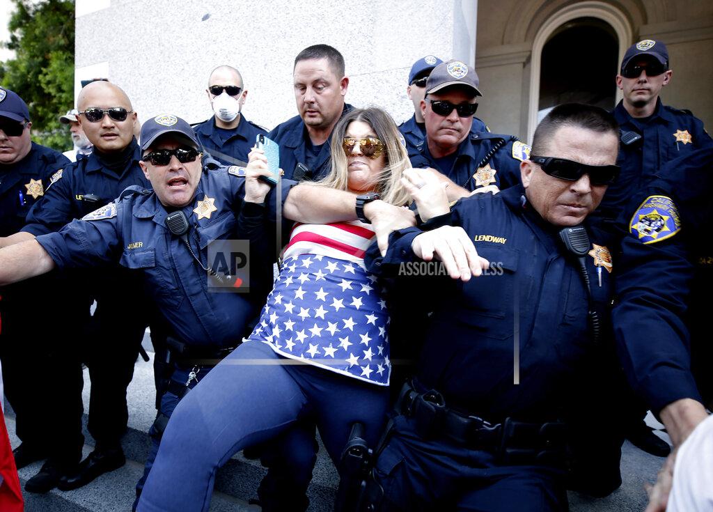 Rich Pedroncelli FILE - In this May 1, 2020, file photo, a protester is detained by California Highway Patrol officers during a demonstration against Gov. Gavin Newsom's stay-at-home orders due to the coronavirus pandemic, at the Capitol in Sacramento, Calif. When President Trump-supporting insurrectionists stormed the U.S. Capitol in an attempt to overturn the presidential election on Wednesday, Jan. 6 2021 the nation was shocked, but not unwarned. A series of dress rehearsals of sorts have played out in statehouses in Michigan, Oregon, Idaho and elsewhere in recent months, with armed protesters forcing their way into buildings. (AP Photo/Rich Pedroncelli, File)