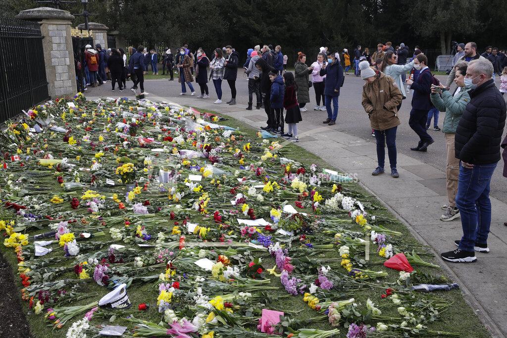 Kirsty Wigglesworth People look at flowers outside Windsor Castle in Windsor, England Sunday, April 11, 2021. Britain's Prince Philip, the irascible and tough-minded husband of Queen Elizabeth II who spent more than seven decades supporting his wife in a role that mostly defined his life, died on Friday. (AP Photo/Kirsty Wigglesworth)