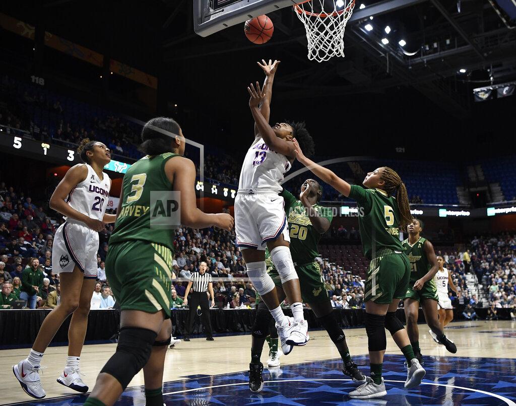 Jessica Hill FILE- In this March 8, 2020 file photo, Connecticut's Christyn Williams makes a basket as South Florida's Elena Tsineke, right, defends during the first half of an NCAA college basketball game in at Mohegan Sun Arena in Uncasville, Conn. Final plans were announced Thursday, Nov. 12, 2020, for 11 days of college basketball in November, inside a modified bubble at the Mohegan Sun resort casino. (AP Photo/Jessica Hill, File)