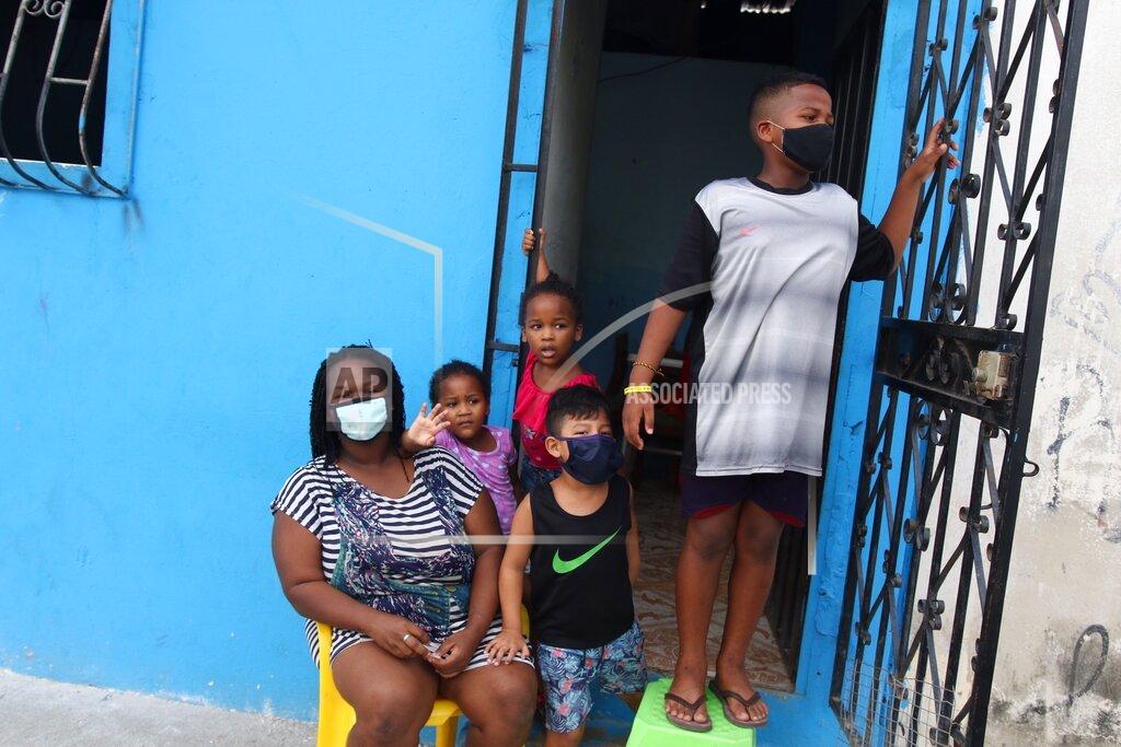 Angel De Jesus FILE - In this April 14, 2020 file photo, a family waits outside their home to receive food handouts from the local government, in the Cristo del Consuelo neighborhood of Guayaquil, Ecuador. In March and April, Guayaquil was a pandemic hellscape of makeshift morgues, hundreds dying at home, bodies left in the street. But Guayaquil has stabilized since then, sending medical teams and equipment elsewhere in Ecuador and taking in virus patients from outside the city. (AP Photo/Angel de Jesus, File)