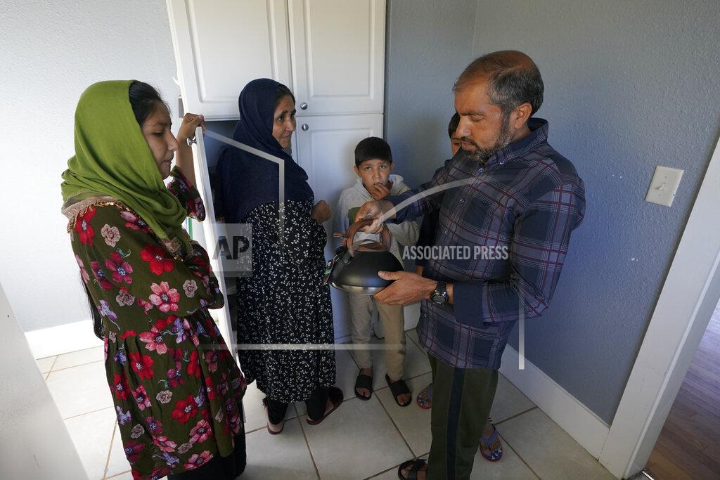 Ted S. Warren Abdul, right, who worked as a mechanic before he left Kabul, Afghanistan with his family about a month ago, shows his family a donated tea kettle as they stand in the kitchen of a rental house, Thursday, Sept. 16, 2021, that has been provided as a place for them to stay in Seattle. The home is owned by Thuy Do, who was nine years old when her family arrived in the United States from Vietnam in the 1980s. Now Do and her husband have offered their vacant rental home to refugee resettlement groups to house newly arriving Afghans in need of a place to stay. (AP Photo/Ted S. Warren)