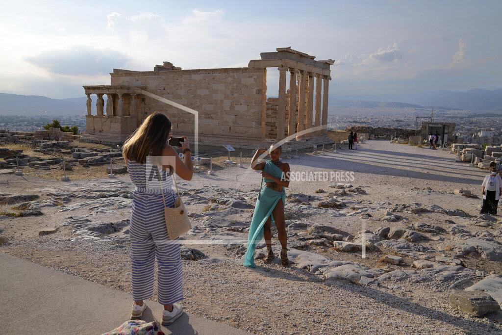 FILE - In this Tuesday, June 8, 2021 file photo, a tourist take photos at the Parthenon temple during a media tour for the Foreign Correspondents organised by the Greek Cultural Ministry at the Acropolis hill in Athens. Europe is opening up to Americans and other visitors after more than a year of COVID-induced restrictions. European governments hope to lure back tourists - and their dollars - back to the continent’s trattorias, vistas and cultural treasures. (AP Photo/Thanassis Stavrakis, File)