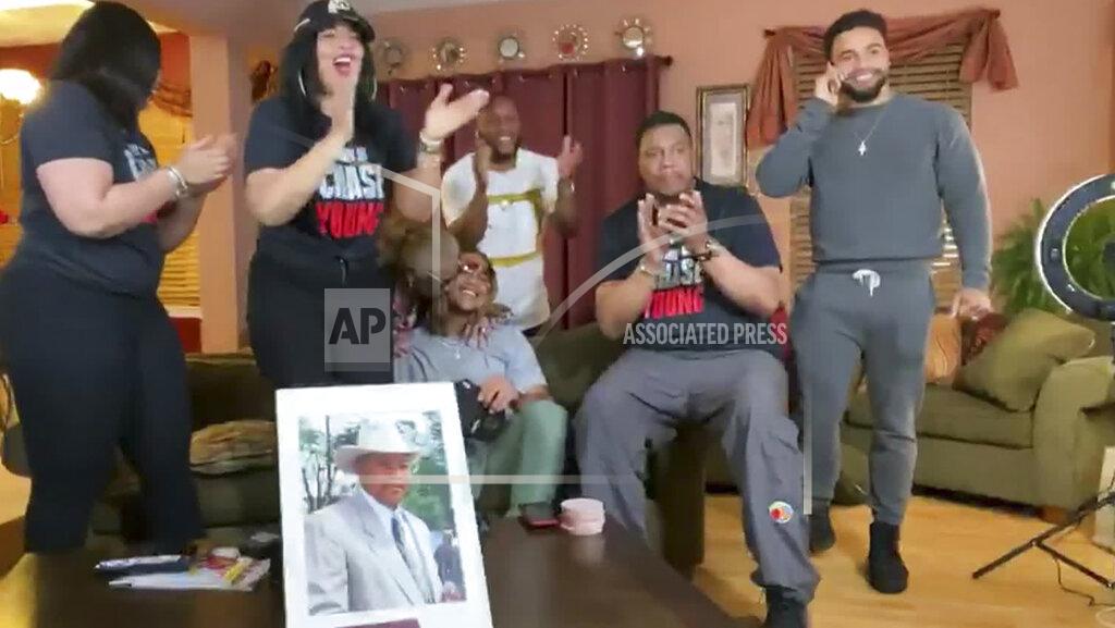 Uncredited CORRECTS LOCATION OF YOUNG TO SEATED IN CENTER, INSTEAD OF AT RIGHT - In this still image from video provided by the NFL, Chase Young, seated in center, talks on his cellphone during the NFL football draft Thursday, April 23, 2020. Young was drafted second by the Washington Redskins. (NFL via AP)