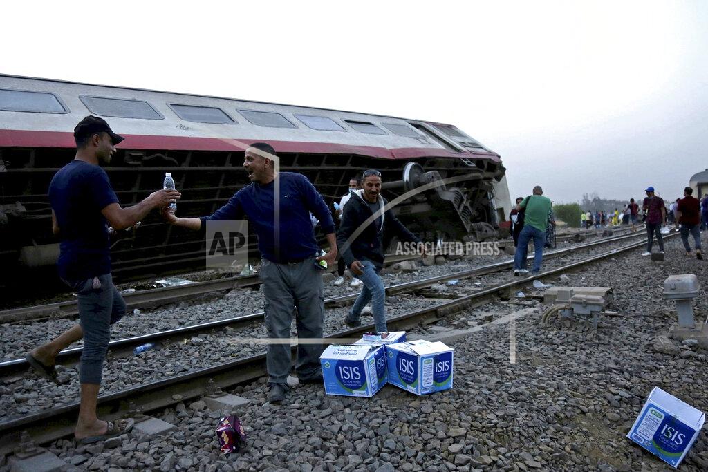 Fadel Dawood People break their fast during the holy month of Ramadan, at the site of a passenger train that derailed injuring around 100 people, near Banha, Qalyubia province, Egypt, Sunday, April 18, 2021. The train was travelling to the Nile Delta city of Mansoura from the Egyptian capital, the statement said. (AP Photo/Fadel Dawood)