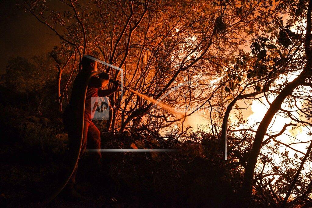 Uncredited A firefighter battles with fire in Kirli village near the town of Manavgat, in Antalya province, Turkey early Friday July 30, 2021. The fire that continued all night could not be brought under control and people living in the village started to evacuate. Wildfires are common in Turkey's Mediterranean and Aegean regions during the arid summer months, although some previous forest fires have been blamed on arson.(AP Photo)