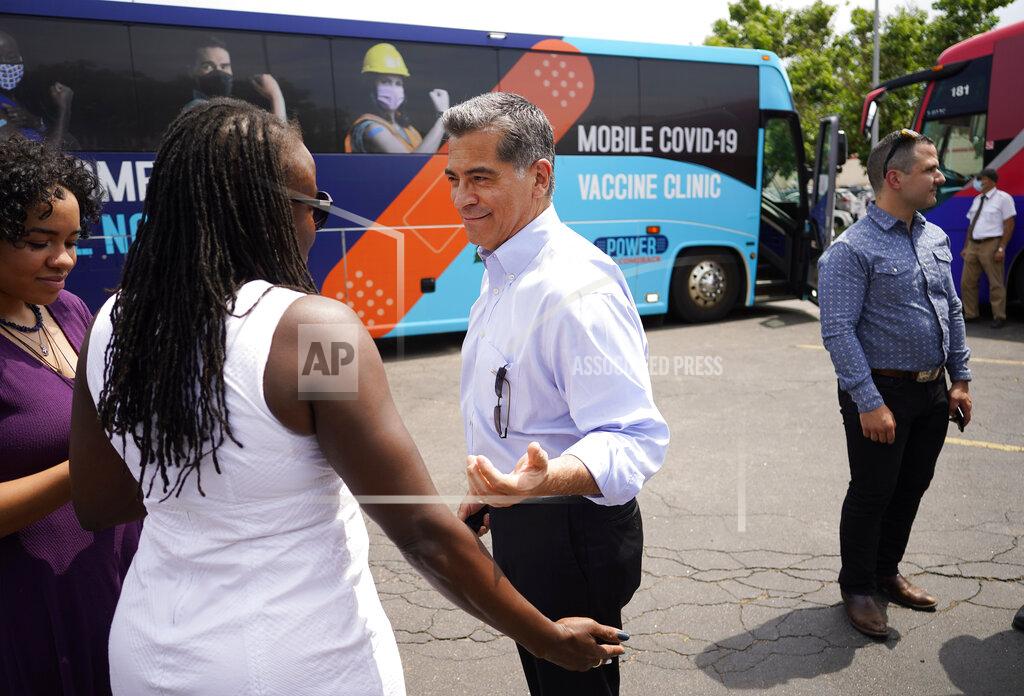 David Zalubowski U.S. Department of Health and Human Services Secretary Xavier Becerra, center, greets well-wishers during a visit to a pair of buses set up as traveling clinics as part of the state's "Vaccines For All" campaign Friday, June 18, 2021, in Aurora, Colo. The buses are being used to distribute COVID-19 vaccines. (AP Photo/David Zalubowski)