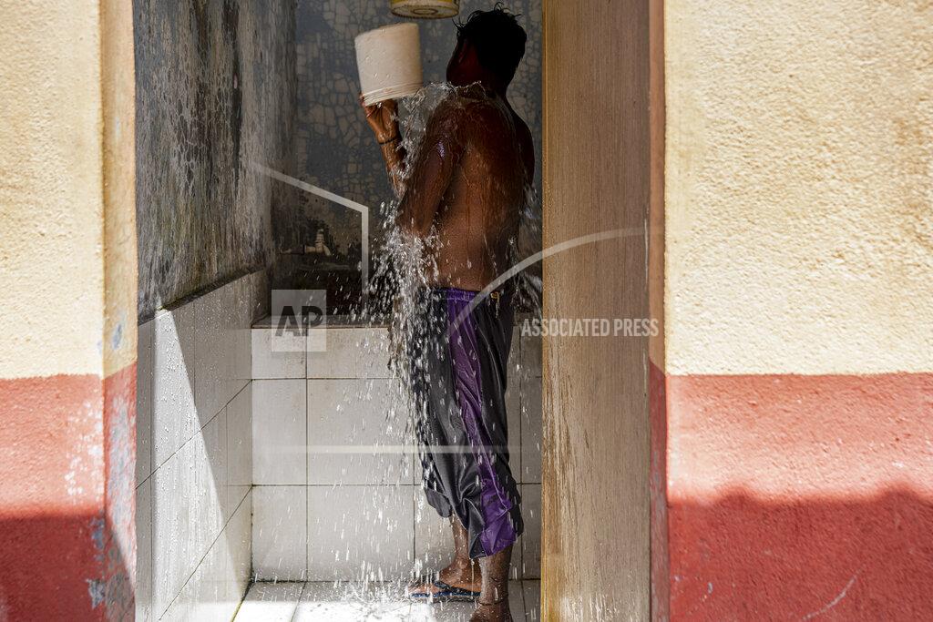 Ore Huiying A worker bathes at a palm oil plantation run by government-owned Felda in peninsular Malaysia, in early 2020. Jum, a former worker who escaped from this same plantation, described to The Associated Press how the company confiscated, and later lost, his Indonesian passport, leaving him vulnerable to arrest and forcing him to hide in the jungle. (AP Photo/Ore Huiying)