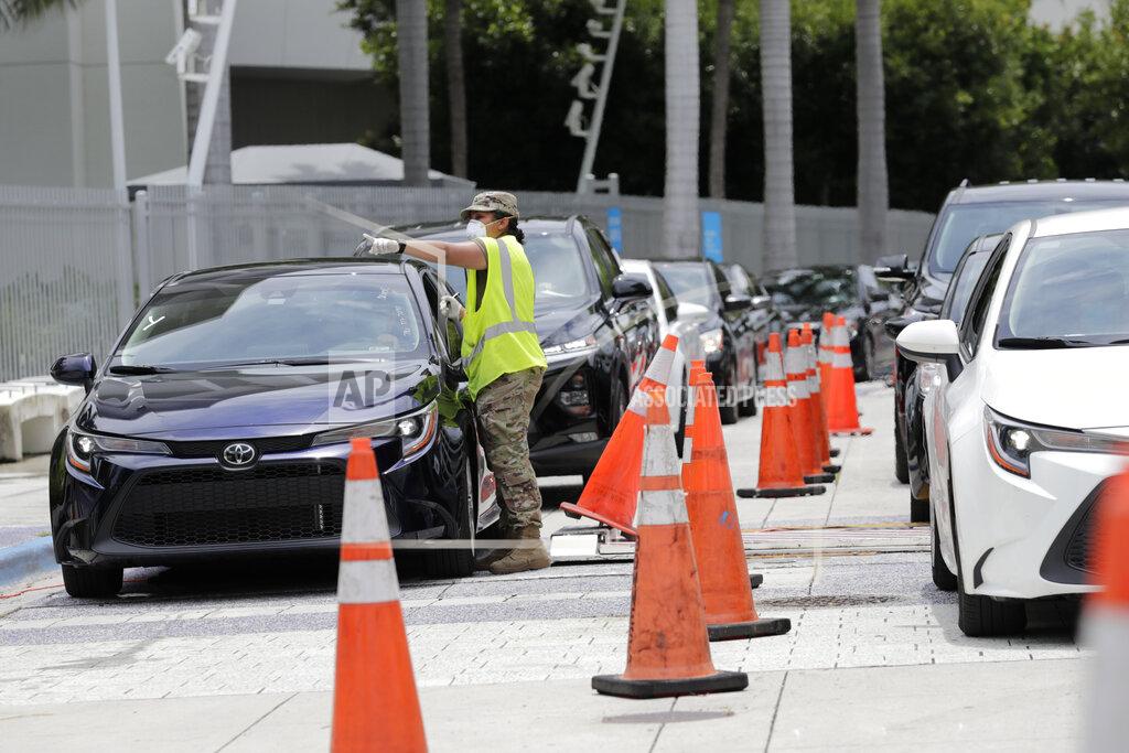 Lynne Sladky A member of the Florida National Guard monitors vehicles waiting in line outside of Marlins Park at a COVID-19 testing site during the coronavirus pandemic, Monday, July 6, 2020, in Miami. The long line of cars each morning as players arrive at work provides a reminder of the risks when they leave. Behavior away from the ballpark will be a big factor in determining whether Major League Baseball's attempt to salvage the 2020 season can succeed. (AP Photo/Lynne Sladky)