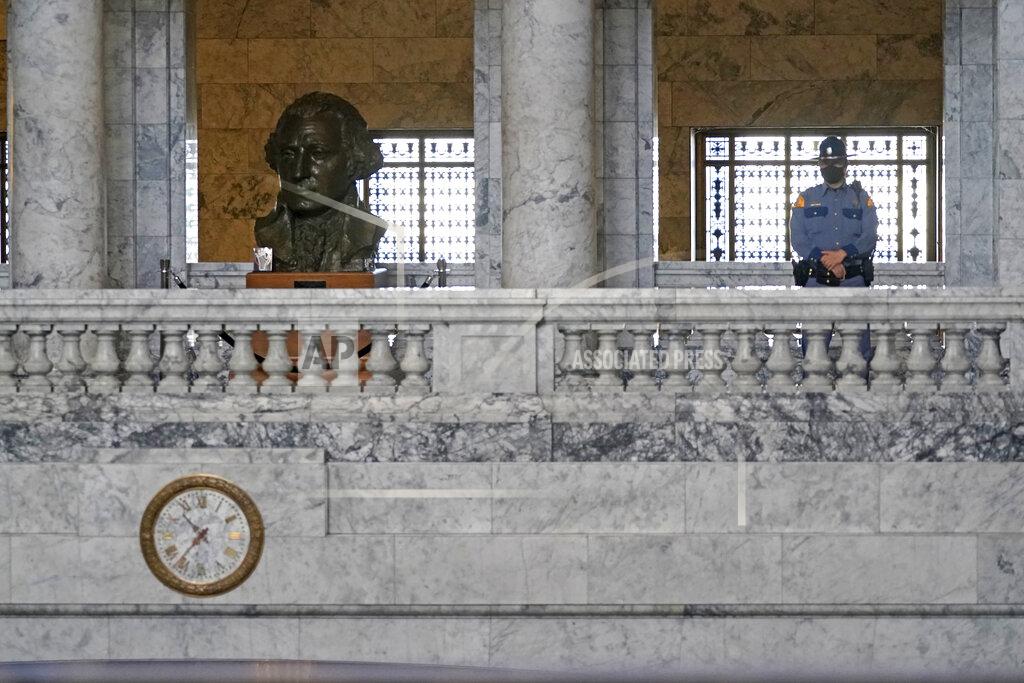 Ted S. Warren FILE - In this Jan. 13, 2021 file photo, a Washington State Patrol trooper stands near a bust of President George Washington in the Legislative Building at the Capitol in Olympia, Wash. The 2021 session of the Washington Legislature ended Sunday, April 25 and lawmakers had no shortage of weighty topics to consider while having to conduct their work amid a pandemic that meant most meetings and votes were conducted remotely. The Capitol building was also closed to the public since last year due to the COVID-19 pandemic, and was surrounded by security fencing and national guard members at times due to fears of protests. (AP Photo/Ted S. Warren, File)