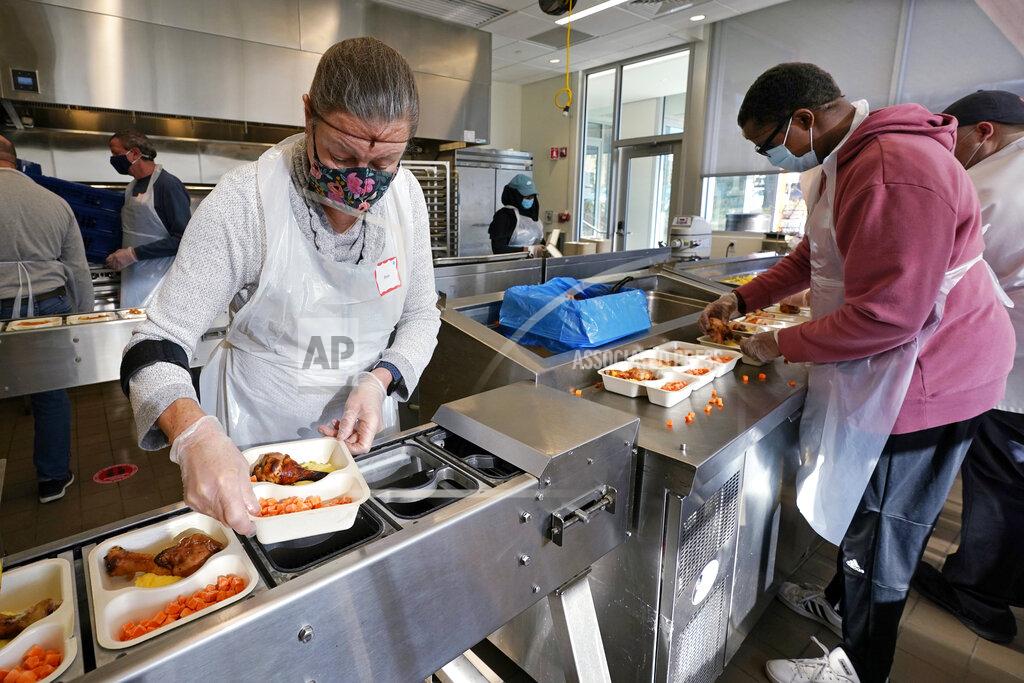 Charles Krupa Volunteers Sheeran Howard, left, and Ibrahim Bahrr, right, package meals at Community Servings, which prepares and delivers scratch-made, medically tailored meals to individuals & families living with critical & chronic illnesses, Tuesday, Jan. 12, 2021, in the Jamaica Plain neighborhood of Boston. Food is a growing focus for insurers as they look to improve the health of the people they cover and cut costs. Insurers first started covering Community Servings meals about five years ago, and CEO David Waters says they now cover close to 40%. (AP Photo/Charles Krupa)
