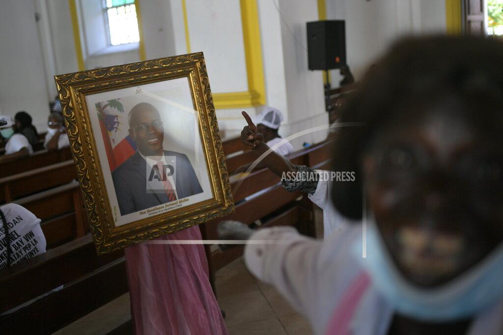 Matias Delacroix People call for justice as they point to a portrait of the late President Jovenel Moïse during a memorial service for him in the Cathedral of Cap-Haitien, Haiti, Thursday, July 22, 2021. Moïse was killed in his home on July 7. (AP Photo/Matias Delacroix)