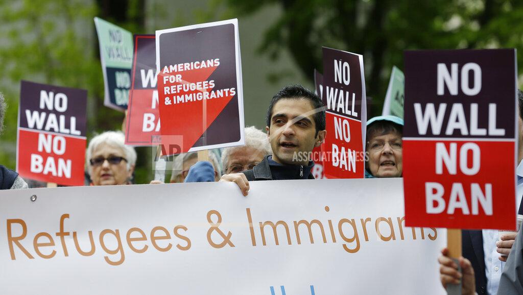 Ted S. Warren FILE - In this May 15, 2017, file photo, protesters hold signs during a demonstration against President Donald Trump's revised travel ban, outside a federal courthouse in Seattle. Refugee advocates, including faith-based groups that President Donald Trump is courting in his re-election bid, called on Congress Thursday, Oct. 1, 2020, to halt his administration’s plans to slash the limit on refugees allowed into the U.S. to a record low, saying it goes against America’s values. (AP Photo/Ted S. Warren, File)